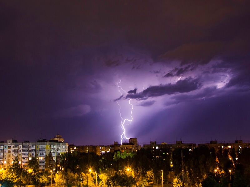 Éclair qui tombe sur des immeubles dans une ville durant la nuit